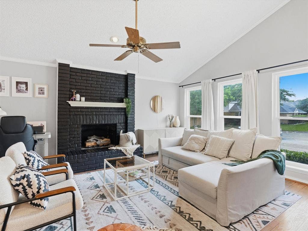 2812 Prescott Drive, Carrollton, TX 75006 Living area featuring a black brick fireplace with a white mantel, vaulted ceilings, and wood-finish flooring