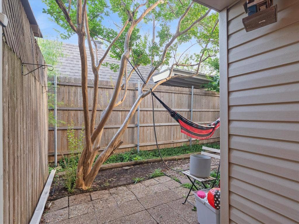 2812 Prescott Drive, Carrollton, TX 75006 Private outdoor area featuring a mature tree, stone patio pavers, wood fencing, and neutral-toned siding