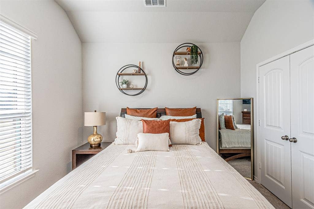 Bedroom featuring vaulted ceilings, a window with blinds, and white bi-fold closet doors