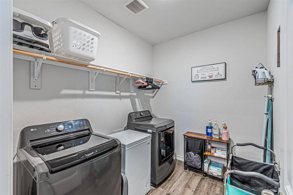 Dedicated laundry area featuring wood-finish flooring, white walls, and a built-in shelving unit with a hanging rod