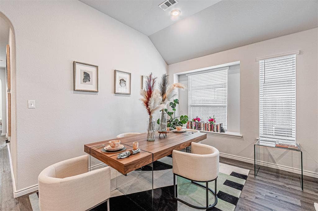 Dining area featuring a vaulted ceiling and wood-finish flooring