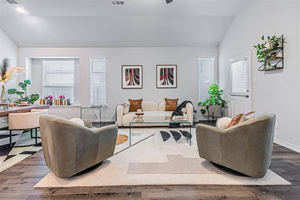 Vaulted ceiling living area featuring wood-finish flooring, multiple windows with blinds, and a built-in wall shelf