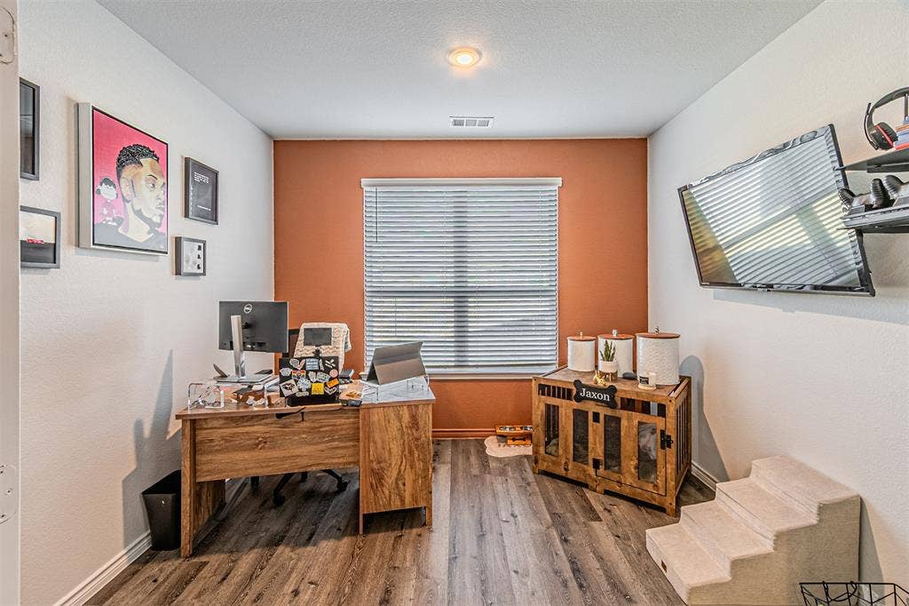 Room featuring wood-finish flooring, a window with horizontal blinds, and a terracotta accent wall