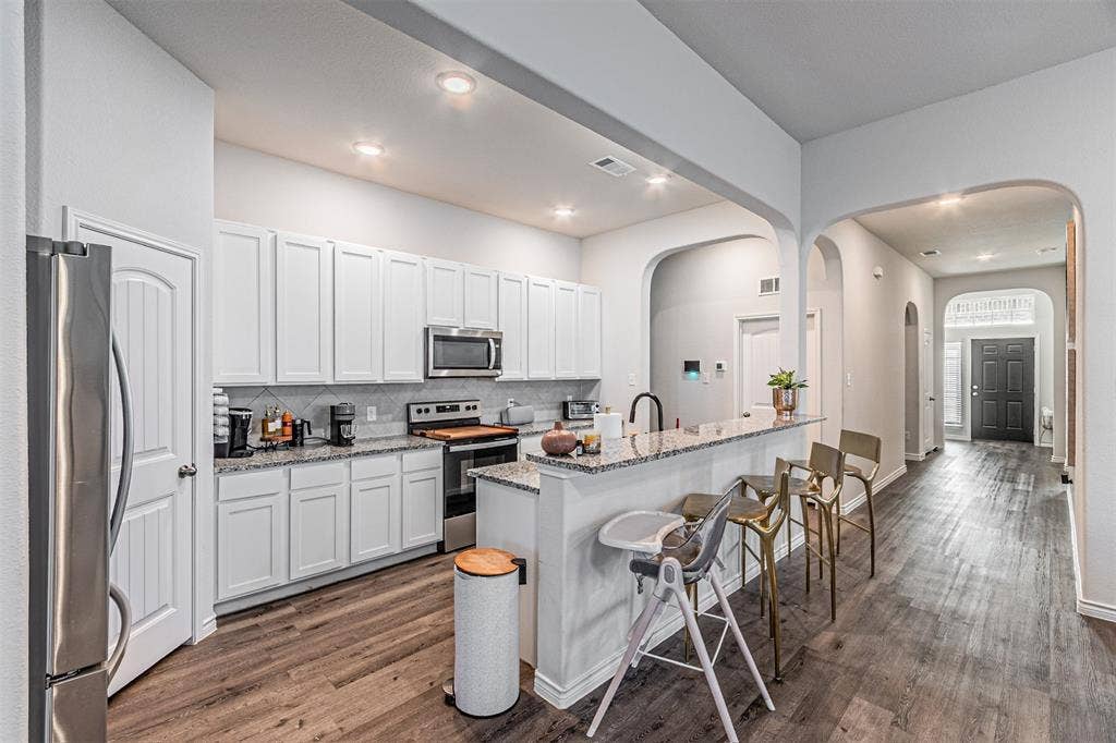 Modern kitchen featuring white cabinetry, granite countertops, and stainless steel appliances