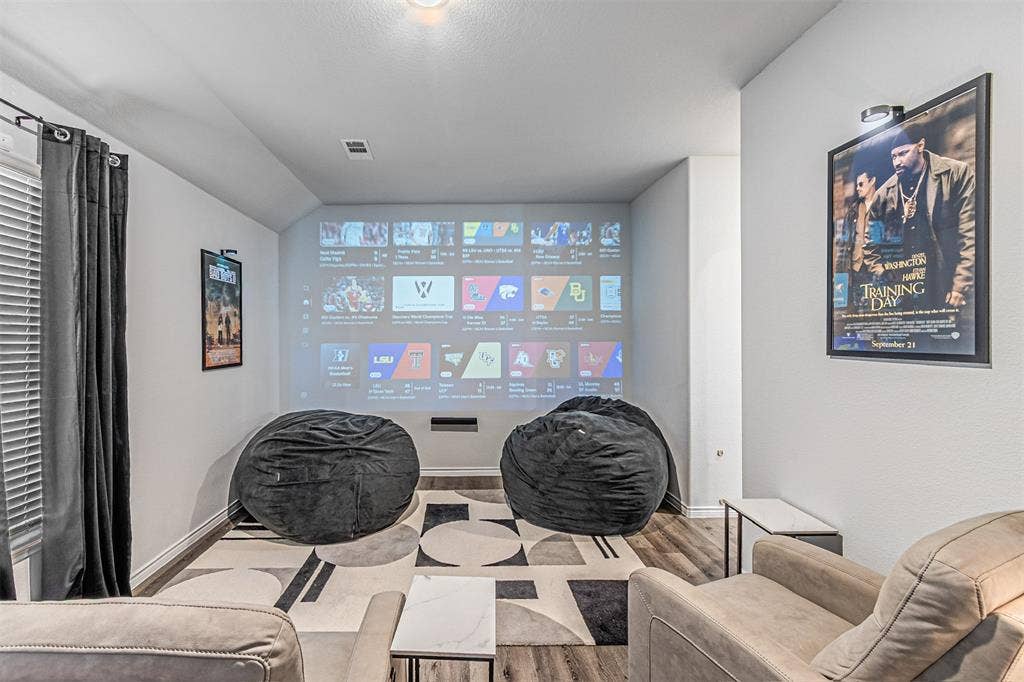 Dedicated media space featuring a large projection screen and wood-finish flooring