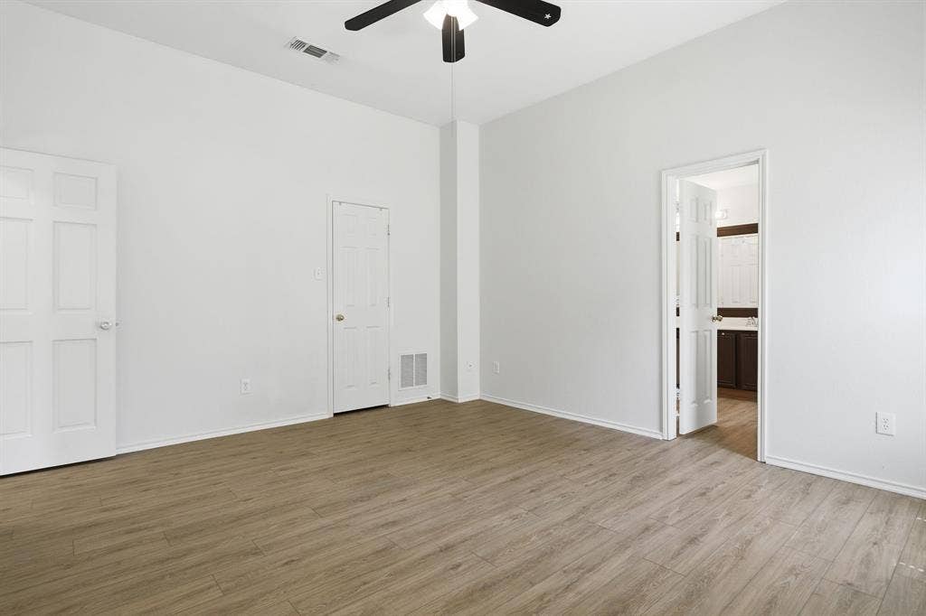Spacious interior room featuring wood-finish flooring, vaulted ceiling, and a ceiling fan with integrated lighting