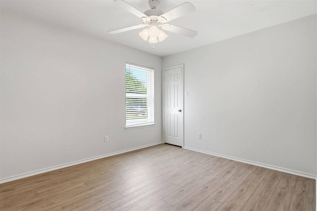 Bright room featuring wood-finish flooring, a ceiling fan with light fixture, and a window with blinds