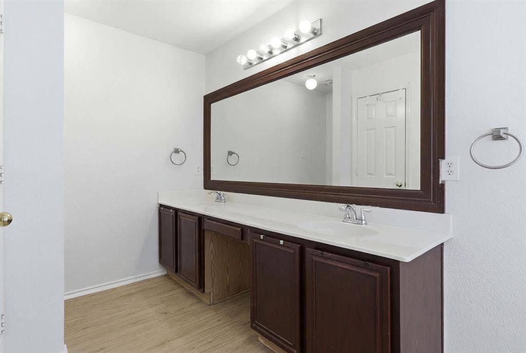 Double vanity featuring wood-finish cabinetry, white countertops, and dual undermount sinks