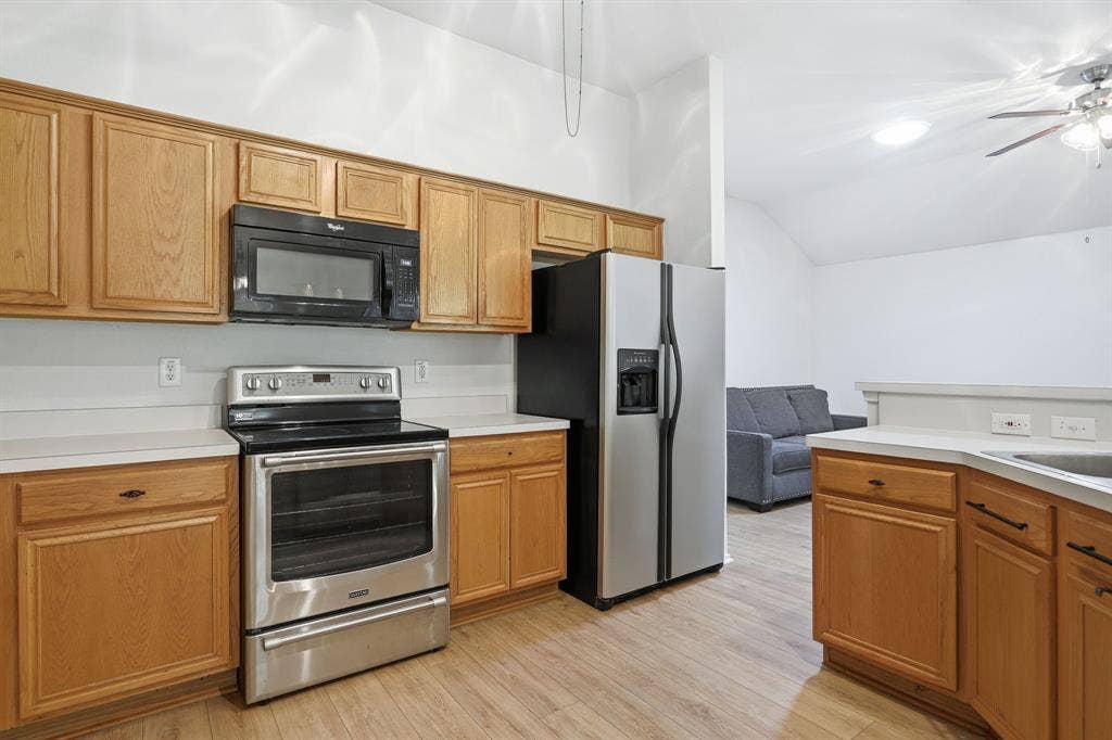 Kitchen featuring wood-finish cabinetry, light countertops, and a wood-finish flooring