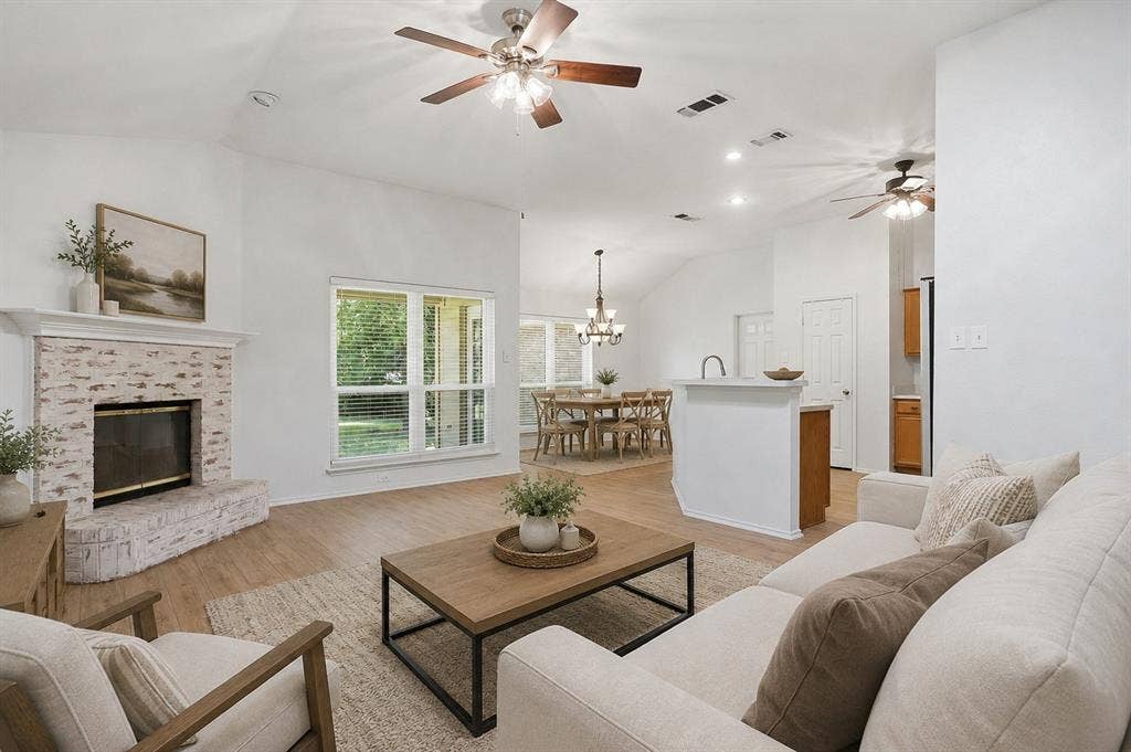 Spacious open-concept living area featuring a vaulted ceiling and wood-finish flooring. *Photo is virtually staged using AI.