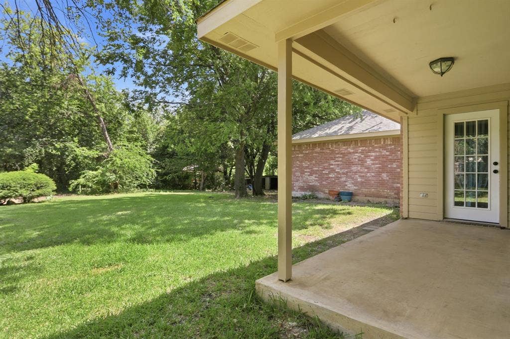 Covered concrete patio overlooking a spacious lawn