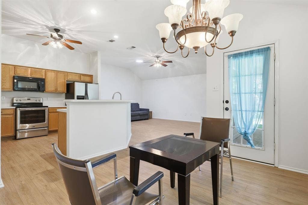 Open-concept living space featuring wood-finish flooring, a kitchen island, stainless steel appliances, and a vaulted ceiling