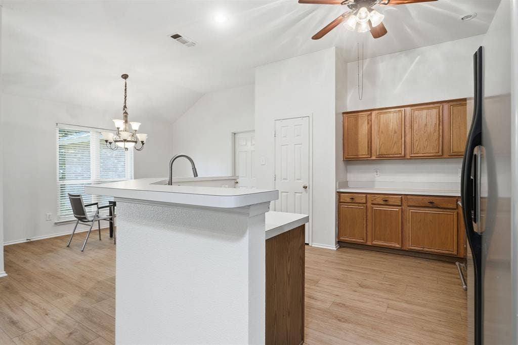 Kitchen area featuring wood-finish flooring, vaulted ceilings, and a breakfast bar with a gooseneck faucet