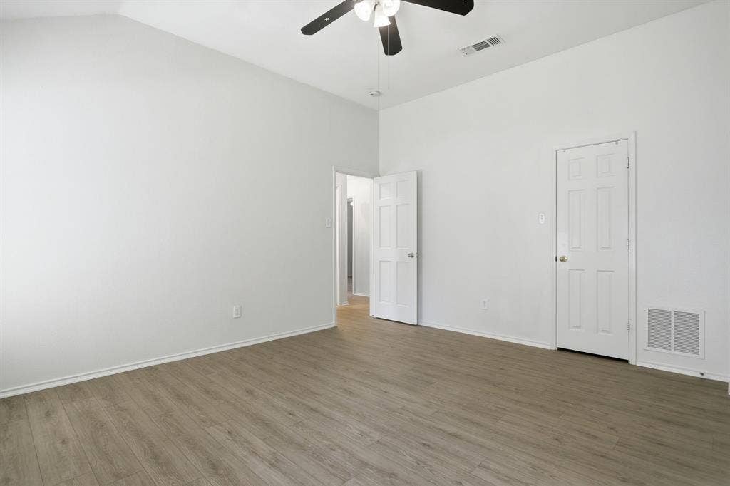 Room featuring wood-finish flooring, white baseboards, and a vaulted ceiling with a ceiling fan
