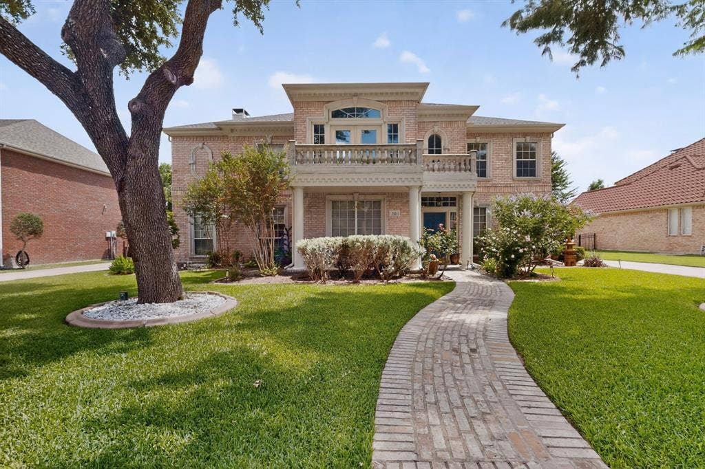 712 Water Oak Drive, Plano, TX 75025 Traditional brick exterior featuring a second-story balcony with balustrade, a gabled entry, and a prominent front porch with columns