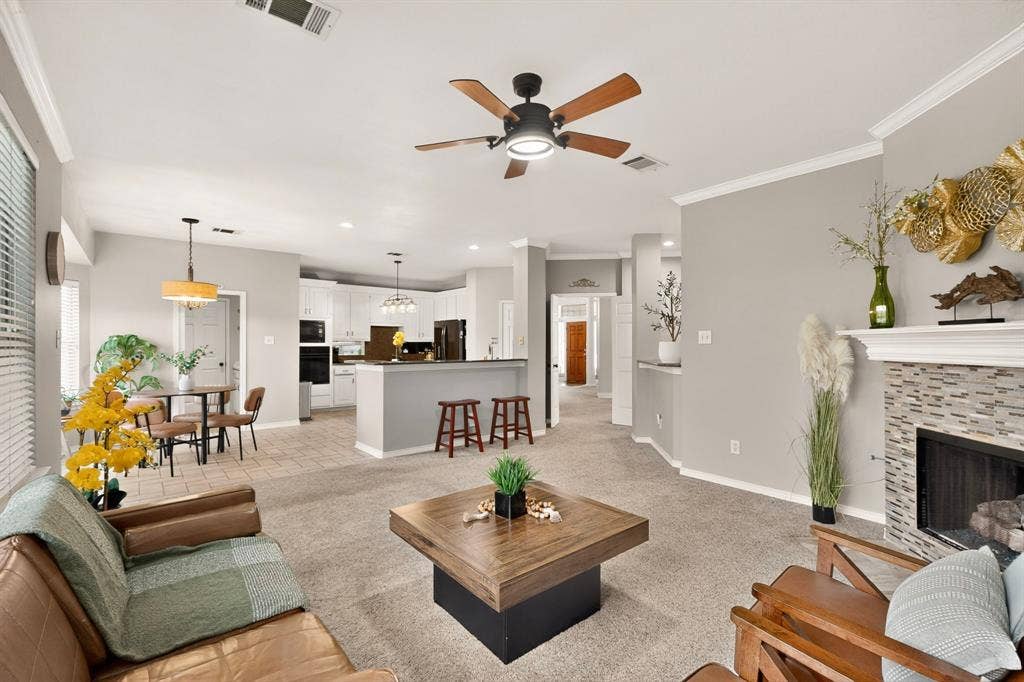 712 Water Oak Drive, Plano, TX 75025 Spacious living area featuring carpet flooring, a ceiling fan with integrated lighting, and crown molding