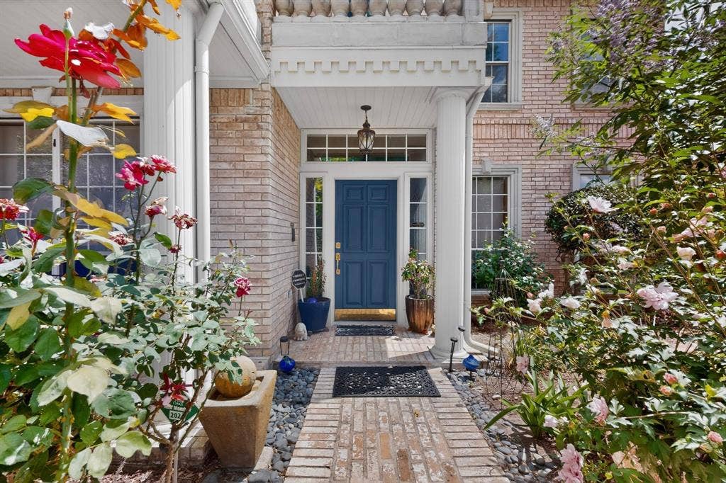 712 Water Oak Drive, Plano, TX 75025 Brick facade entrance featuring a covered porch with white columns, a blue paneled door, and a transom window