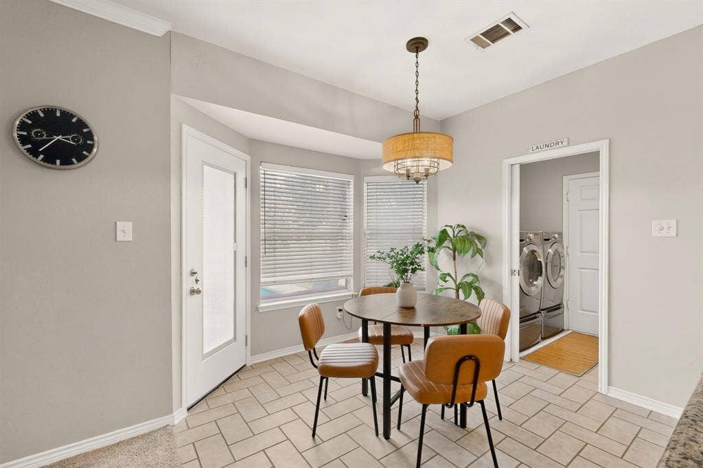 712 Water Oak Drive, Plano, TX 75025 Tiled flooring throughout this bright breakfast nook, featuring a bay window, decorative chandelier, and exterior door with frosted glass panel