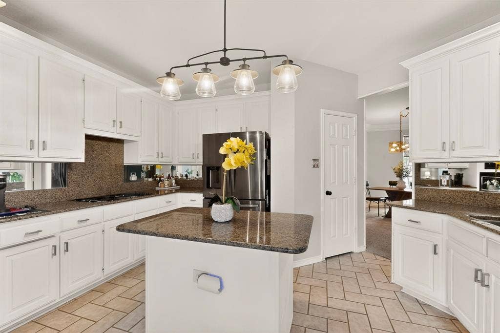 712 Water Oak Drive, Plano, TX 75025 Kitchen featuring white cabinetry, granite countertops, a central island, stainless steel refrigerator, and herringbone tile flooring