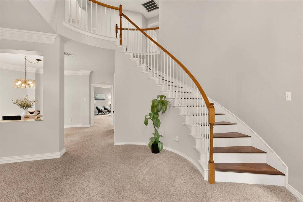 712 Water Oak Drive, Plano, TX 75025 Curved staircase with wood-finish treads and balusters, white risers, and a matching handrail
