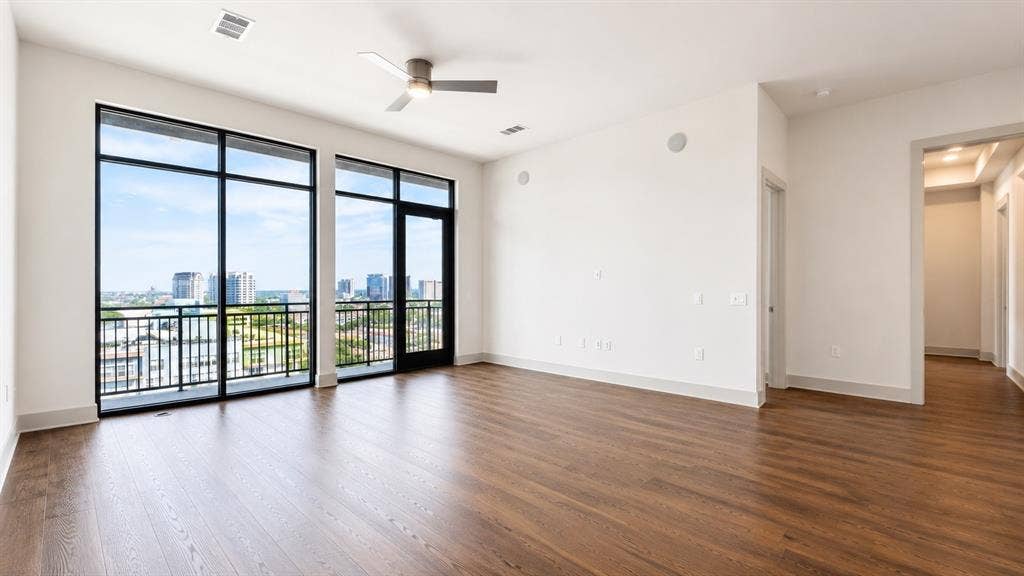 3330 Oak Grove Avenue, #1307, Dallas, TX 75204 Expansive window wall with black frames, a sliding glass door to an outdoor balcony, and cityscape scenery