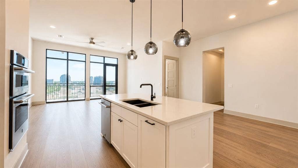 3330 Oak Grove Avenue, #1307, Dallas, TX 75204 Kitchen island featuring a quartz countertop, integrated sink with matte black faucet, and pendant lighting