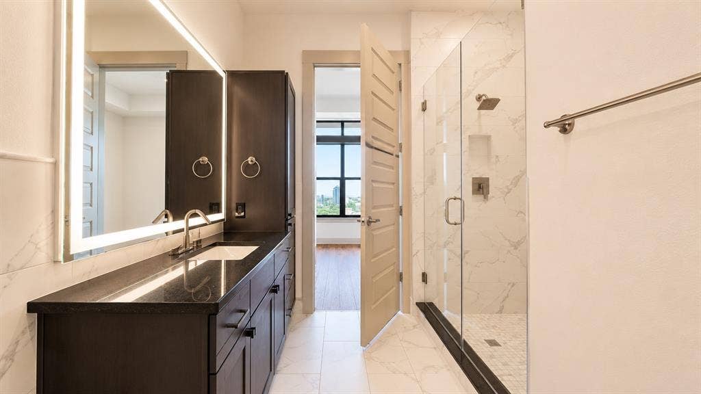 3330 Oak Grove Avenue, #1307, Dallas, TX 75204 Bathroom featuring a spacious walk-in shower with a glass enclosure, rainfall showerhead, and a built-in niche
