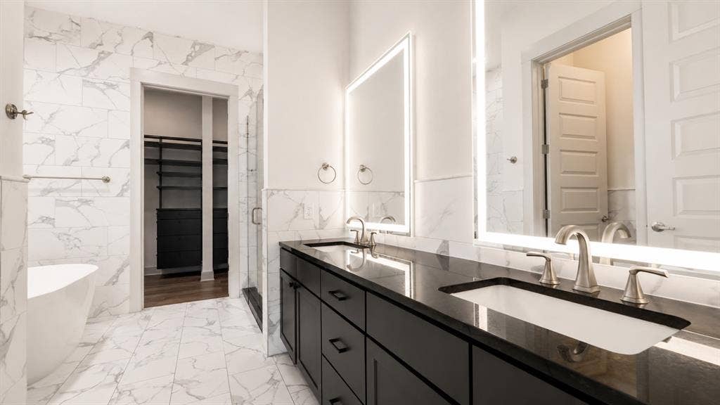 3330 Oak Grove Avenue, #1307, Dallas, TX 75204 Double vanity with dark cabinetry, integrated sinks, and backlit mirrors