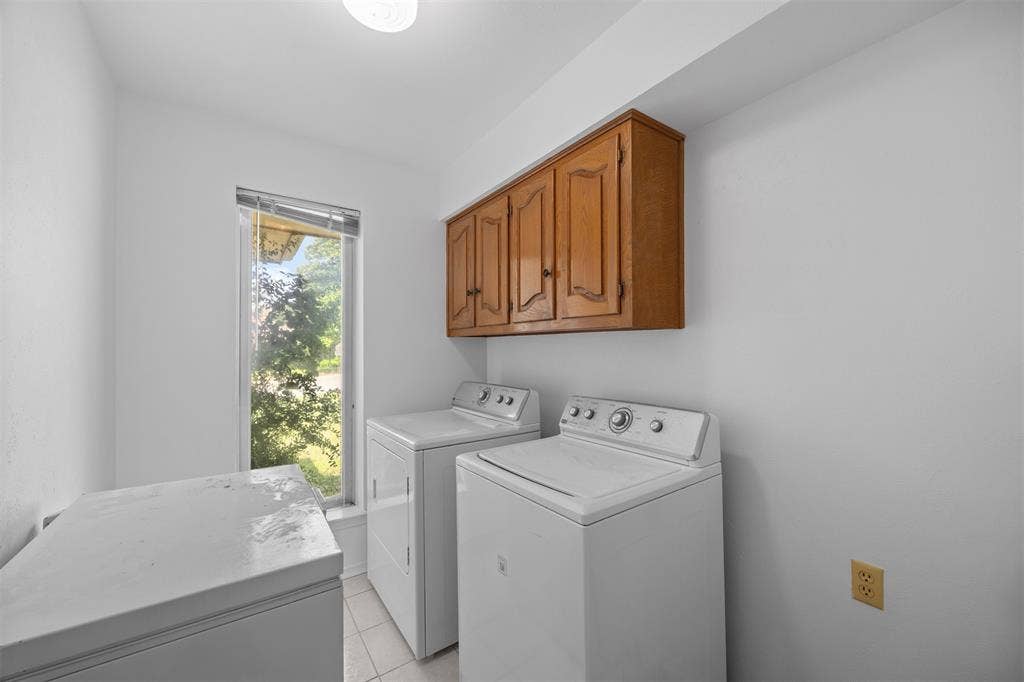 2125 Woodbrook Street, Denton, TX 76205 Utility room featuring a window, built-in wooden cabinetry, recessed ceiling lighting, and tiled flooring