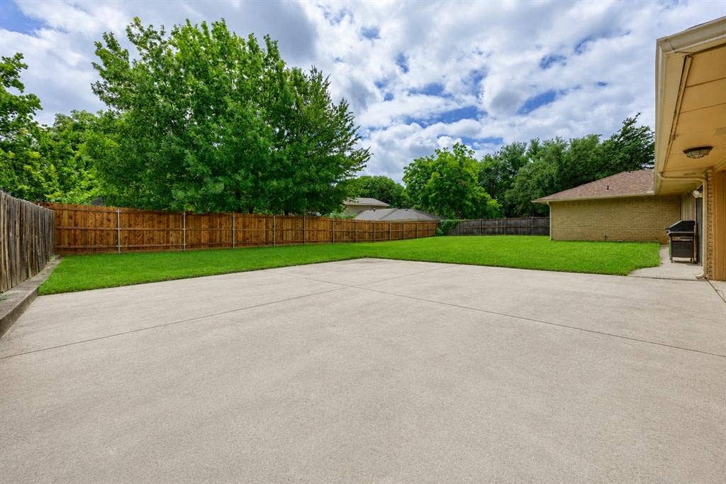 2125 Woodbrook Street, Denton, TX 76205 Expansive concrete patio with a lush green lawn and mature perimeter trees