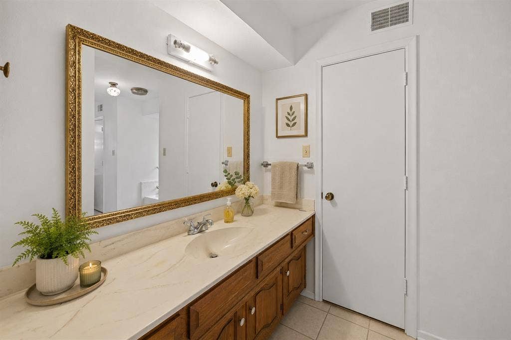 2125 Woodbrook Street, Denton, TX 76205 Long vanity with a light-toned countertop, integrated sink, and wood-finish cabinetry