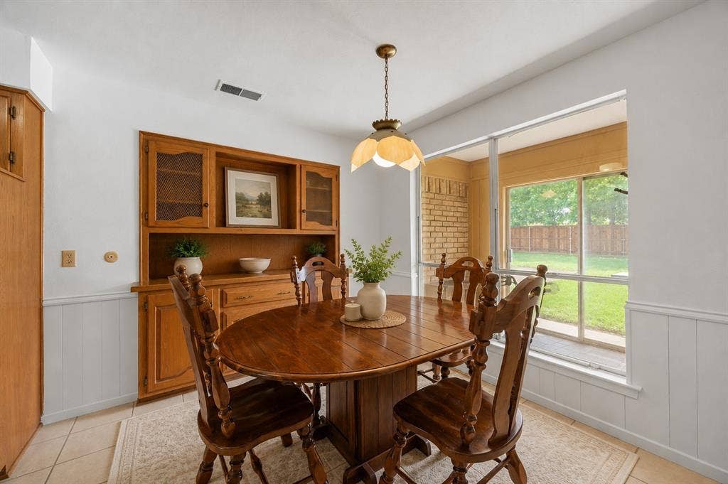 2125 Woodbrook Street, Denton, TX 76205 Dining area with a built-in wood hutch, tiled flooring, white wainscoting, and a large window overlooking the backyard