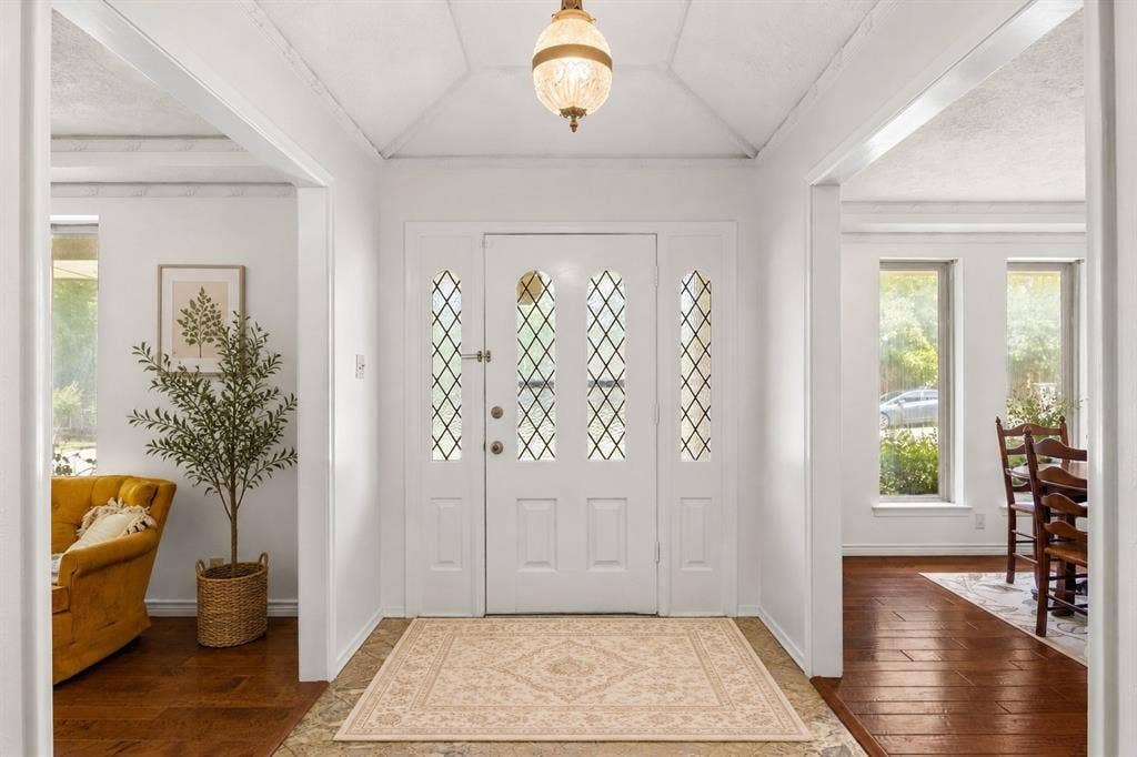 2125 Woodbrook Street, Denton, TX 76205 Entryway featuring a white door with decorative glass inserts, a vaulted ceiling, a brass pendant light fixture, tile flooring, and arched doorways opening to adjacent rooms