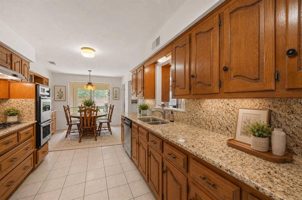 2125 Woodbrook Street, Denton, TX 76205 Galley kitchen featuring wood cabinetry, speckled countertops, tile flooring, and integrated double ovens