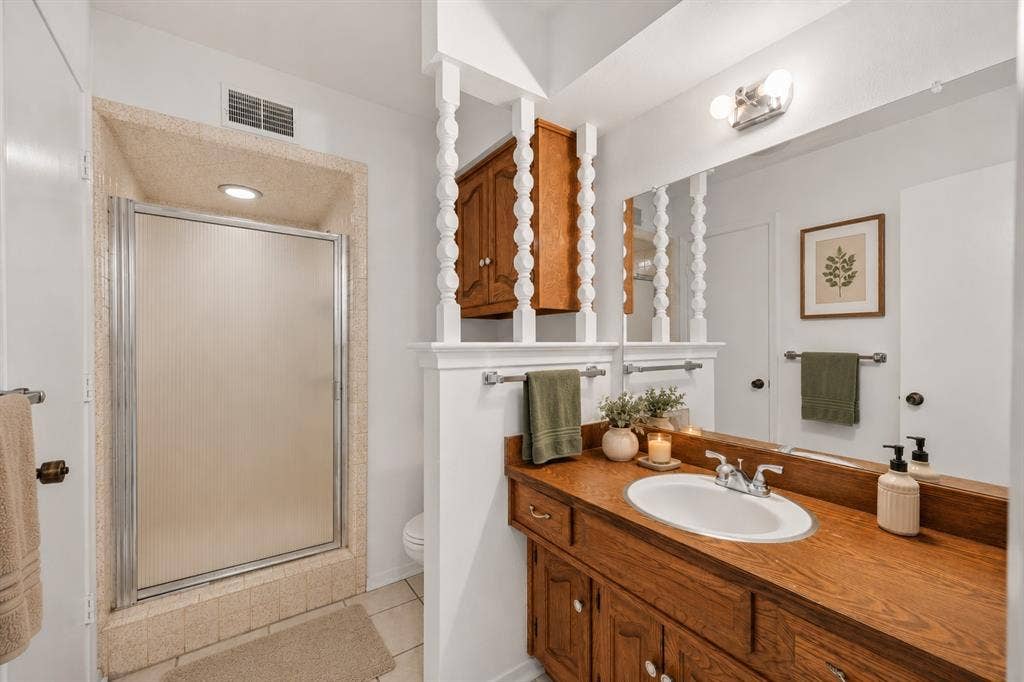 2125 Woodbrook Street, Denton, TX 76205 Bathroom vanity with a wood-finish countertop and an integrated white oval sink, complemented by a large wall-mounted mirror