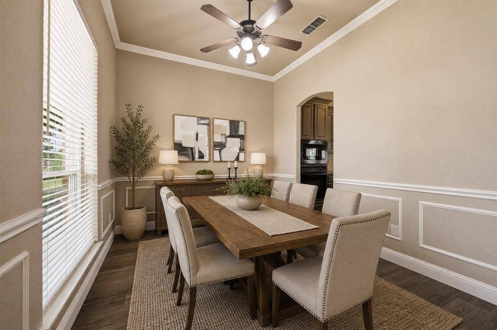 **Virtually staged** Dining area featuring wood-finish flooring, wainscoting, crown molding, and an arched doorway