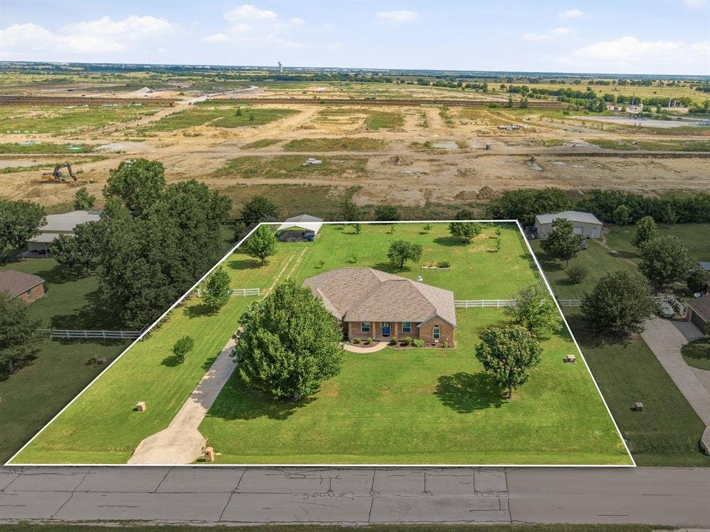Expansive lot featuring a brick residence with a hip roof, a paved driveway, and mature landscaping