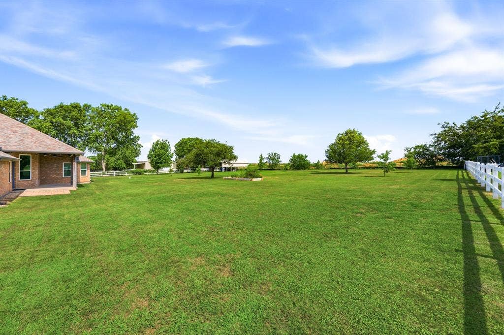 Expansive green lawn with a white fence border