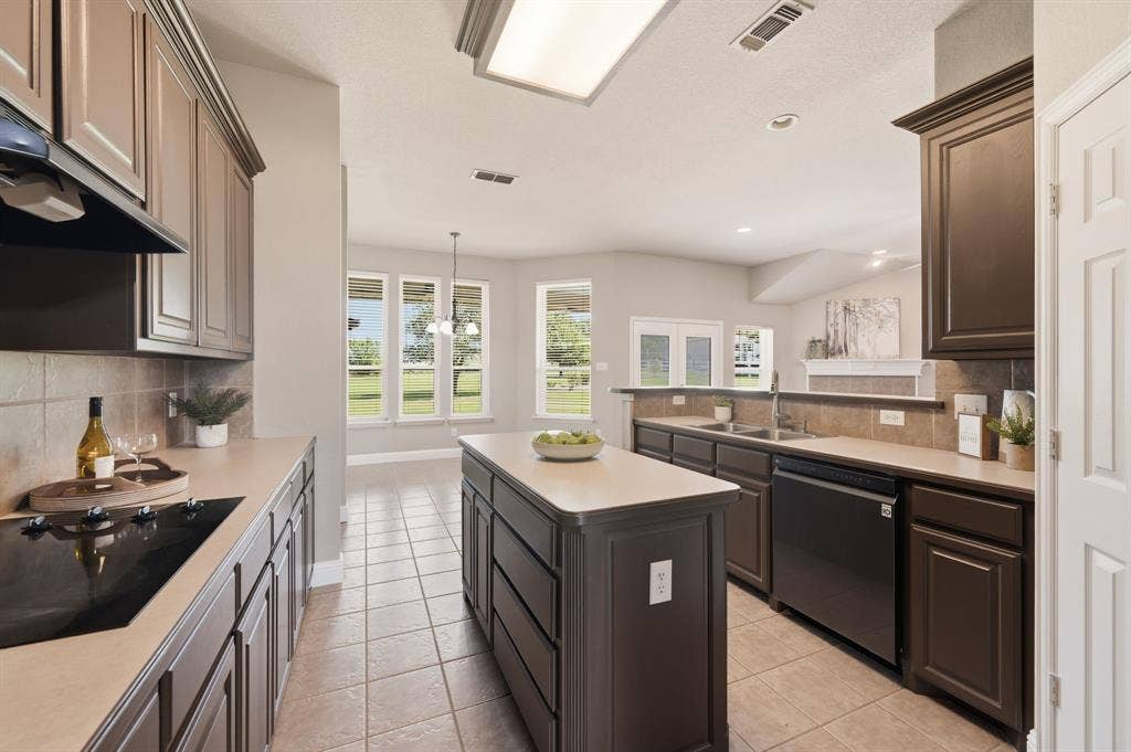Kitchen featuring an island, tile flooring, built-in cooktop, and dark cabinetry