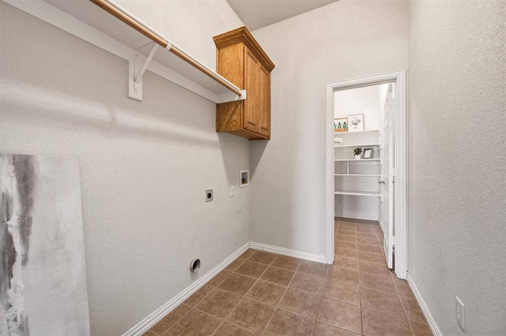 Laundry room featuring tile flooring, neutral wall paint, and a built-in wood-finish cabinet