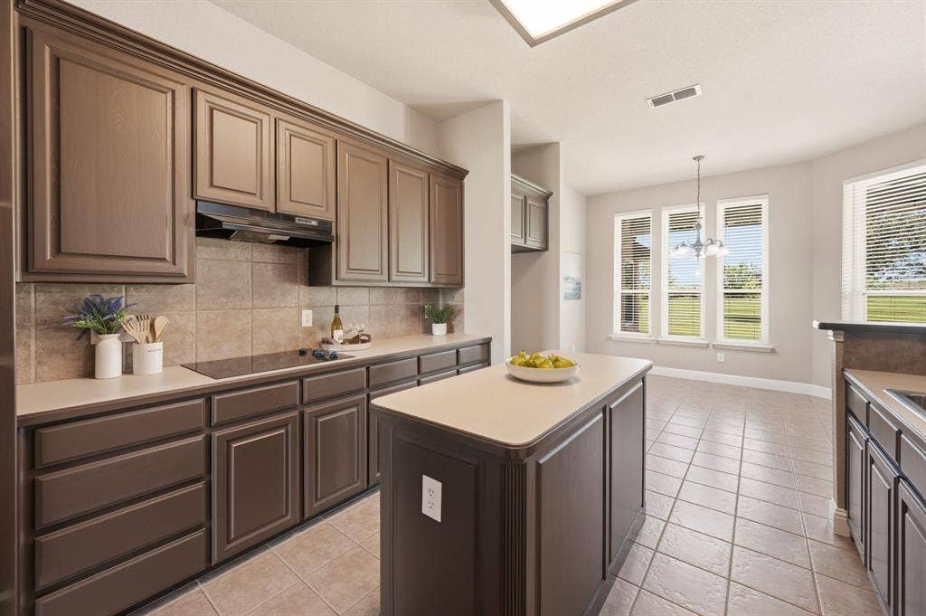 Kitchen featuring dark wood cabinetry, light countertops, a tile backsplash, and an electric cooktop