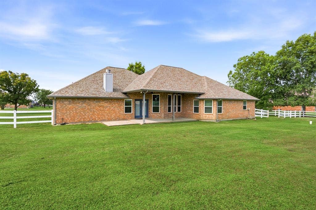 Expansive green lawn surrounds a brick exterior home with a gabled roof