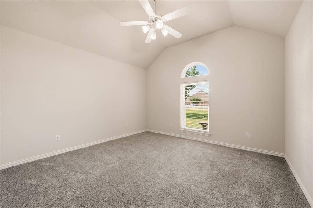 Spacious bedroom featuring vaulted ceilings, neutral-toned walls, and plush grey carpeting