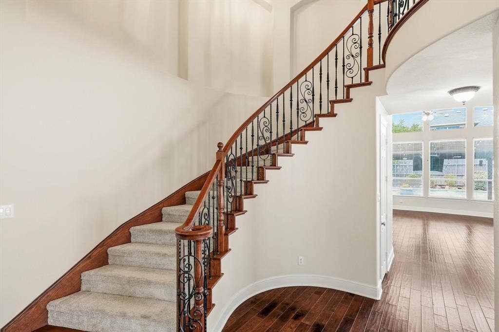 509 Wentworth Lane, Murphy, TX 75094 Curved staircase with wood-finish treads, carpeted risers, and ornate metal balusters