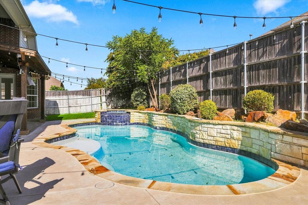 509 Wentworth Lane, Murphy, TX 75094 Swimming pool with stone surround and waterfall feature