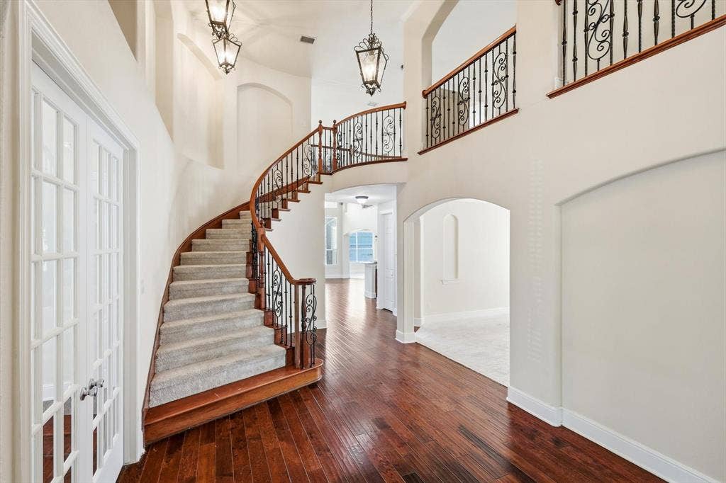 509 Wentworth Lane, Murphy, TX 75094 Grand foyer with wood-finish flooring and a curved staircase featuring wood banisters and wrought iron balusters