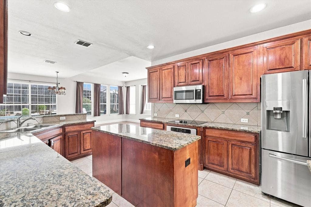 509 Wentworth Lane, Murphy, TX 75094 Kitchen featuring a center island, extensive cabinetry, tile flooring, and stainless steel appliances