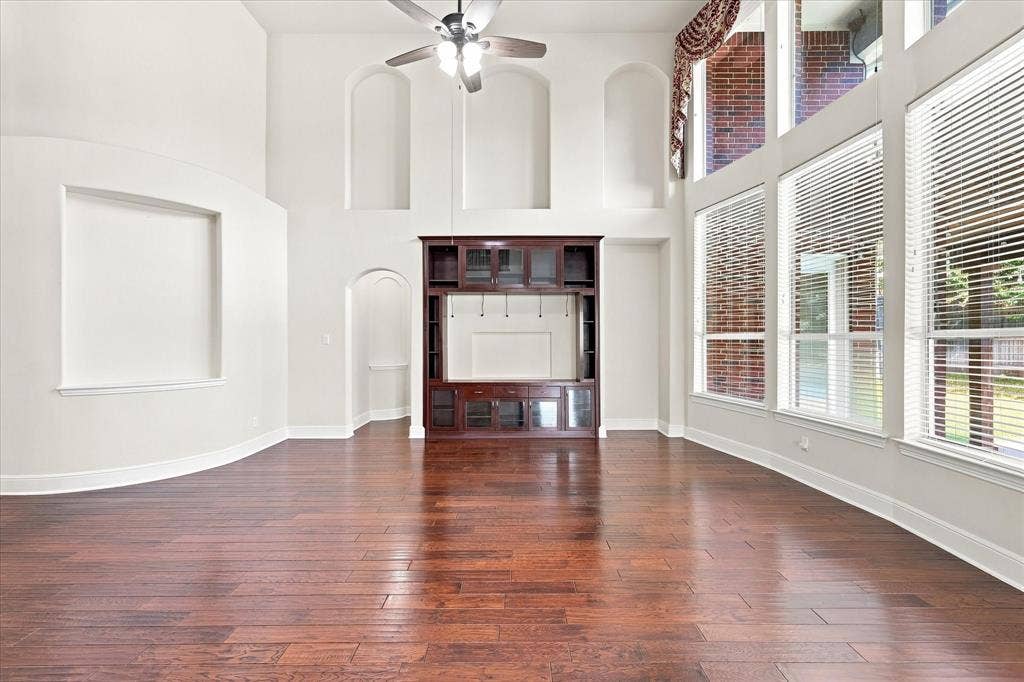 509 Wentworth Lane, Murphy, TX 75094 Wood-finish flooring, built-in entertainment center, high ceilings, large windows with blinds, and architectural wall niches