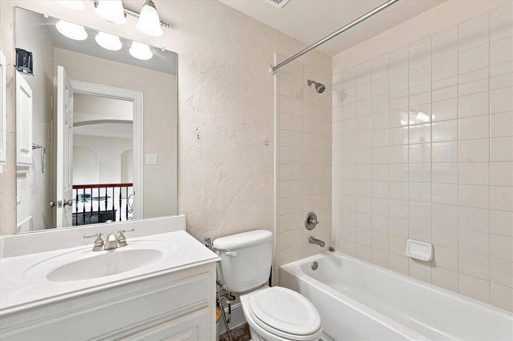 509 Wentworth Lane, Murphy, TX 75094 Bathroom featuring a vanity with an integrated sink, a three-bulb light fixture, a toilet, and a shower-bathtub combination with white tiled walls