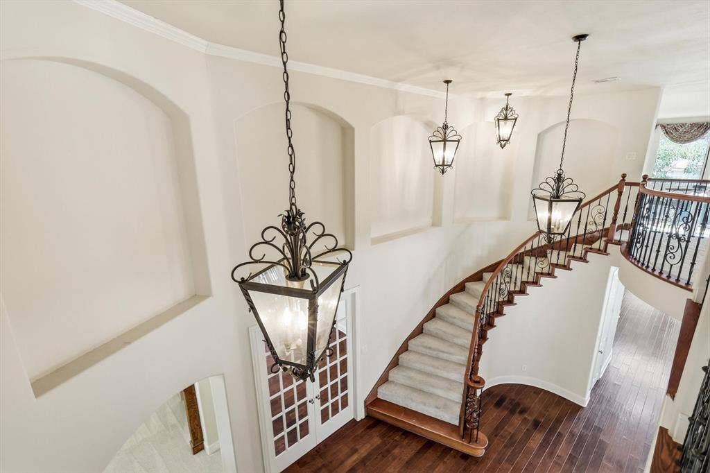 509 Wentworth Lane, Murphy, TX 75094 Grand curved staircase featuring wood-finish flooring, wrought iron balusters, and overhead decorative lanterns